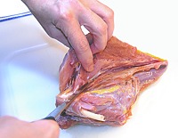 Pulling the breast meat away from the breastbone.